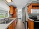 Long view of kitchen with wood cabinets, stainless steel appliances, and vinyl flooring at 512 Ashwood Dr, Venice, FL 34285