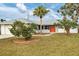 Florida home with orange door, palm trees, and well-maintained lawn at 5221 Lemon Bay Dr, Venice, FL 34293