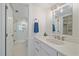 Well-lit bathroom featuring white vanity, glass-enclosed shower, and storage at 5790 Midnight Pass Rd # 602, Sarasota, FL 34242