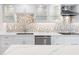 White kitchen featuring a stainless steel sink, stylish cabinetry, unique backsplash and modern appliances, creating a functional culinary space at 5790 Midnight Pass Rd # 602, Sarasota, FL 34242