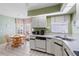Kitchen with white cabinets, appliances, tile flooring, and a dining nook with wood table set by the windows at 704 Harrington Lake S Dr # 6, Venice, FL 34293