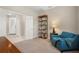 Cozy bedroom with a blue accent chair, decorative bookcase, and neutral-toned walls and carpeting at 12837 Oriago St, Venice, FL 34293