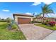 Elegant single-story home with a brick driveway, a two-car garage, and lush green landscaping at 12837 Oriago St, Venice, FL 34293