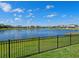 Breathtaking lake view framed by a black fence, showcasing a row of beautiful homes at 5930 Anise Dr, Sarasota, FL 34238