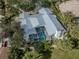 Aerial view of home with metal roof, screened pool, chimney, mature landscaping and white picket fence at 705 Armada N Rd, Venice, FL 34285