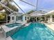 Screened in pool and spa with light blue tiles, surrounded by seating area and white exterior of home at 705 Armada N Rd, Venice, FL 34285