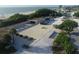 Aerial view of a building complex near a beach, featuring a courtyard, parking, and surrounding greenery at 107 Louella Ln, Nokomis, FL 34275