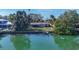 Backyard view from the water featuring a quaint home with a screened lanai overlooking a lush green lawn and waterfront access at 107 Louella Ln, Nokomis, FL 34275