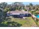 A backyard with a well-maintained lawn, a screened porch, and a glimpse of a swimming pool provides an ideal outdoor setting at 107 Louella Ln, Nokomis, FL 34275