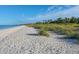Beautiful sandy beach with gentle waves, sea oats, and clear blue skies in a serene coastal setting at 107 Louella Ln, Nokomis, FL 34275