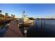 Picturesque boat dock featuring a large yacht, wooden pier, and serene waterfront setting under a clear sky at 107 Louella Ln, Nokomis, FL 34275