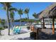 Inviting outdoor bar area featuring palm trees, a thatched roof, and seating with a serene waterfront backdrop at 107 Louella Ln, Nokomis, FL 34275