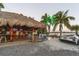 Lively outdoor bar area with thatched roof, TVs, and a sleek white sports car parked nearby at 107 Louella Ln, Nokomis, FL 34275