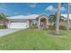Charming single-story home with a white roof, arched entry, and lush landscaping at 1558 Belfry Dr, Venice, FL 34292