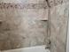 Close-up of a tiled shower with a handheld sprayer and corner shelves at 201 Auburn Woods Cir, Venice, FL 34292