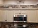 White kitchen cabinets with stainless steel microwave and stone tile backsplash at 201 Auburn Woods Cir, Venice, FL 34292