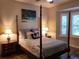 Serene main bedroom with a four-poster bed, shuttered windows, and coastal decor at 201 Auburn Woods Cir, Venice, FL 34292