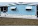 Charming blue home featuring awnings and well-maintained front yard with garden feature at 356 Longwood Dr, Venice, FL 34285