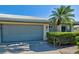 Attached two-car garage with gray doors and a manicured shrub on a sunny single story villa at 3117 Heron Shores Dr, Venice, FL 34293