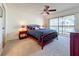 Comfortable carpeted bedroom features a ceiling fan and sliding glass doors to the balcony at 654 Bird Bay E Dr # 206, Venice, FL 34285