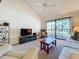 Comfortable living room with vaulted ceilings, fan, plush seating, and a sliding glass door to balcony at 654 Bird Bay E Dr # 206, Venice, FL 34285