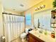Well-lit bathroom featuring a white shower curtain, single sink vanity with an updated mirror and modern lighting at 8307 Glover Ave, North Port, FL 34291