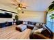 Comfortable living room features a large sectional sofa, ceiling fan, and wood-look laminate flooring at 8307 Glover Ave, North Port, FL 34291