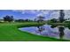 Picturesque view of a serene water hazard with a lush green golf course and blue sky reflecting in the water at 111 Woodbridge Dr # 204, Venice, FL 34293