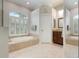 Bright bathroom with soaking tub, framed windows, and tiled flooring at 1206 Tuscany Blvd, Venice, FL 34292