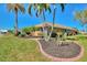 Well-manicured front yard with lush green lawn, landscaping, palm trees, and a paved walkway to the home at 1815 Killdeer Ct, Venice, FL 34293