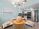 Chic dining area features a glass-top table next to a modern kitchen with stainless steel appliances and white cabinetry at 1423 Avenida Del Circo # 1C, Venice, FL 34285