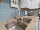 A double stainless steel kitchen sink with a modern faucet and granite countertops at 1423 Avenida Del Circo # 1C, Venice, FL 34285