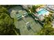 Aerial view of well-maintained tennis courts next to lush greenery and a swimming pool at 256 Royal Oak Way, Venice, FL 34292