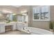 A luxurious bathroom featuring dual vanities, a soaking tub, decorative wallpaper, and tiled floors at 400 Maraviya Blvd, Nokomis, FL 34275