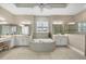 A luxurious bathroom featuring dual vanities, a soaking tub, decorative wallpaper, and tiled floors at 400 Maraviya Blvd, Nokomis, FL 34275