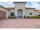 Inviting front exterior featuring a well-maintained lawn, brick driveway, and elegant blue double-door entrance at 400 Maraviya Blvd, Nokomis, FL 34275
