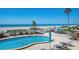 Community pool with lounge chairs, beach access, and tropical foliage, set against a scenic beachfront backdrop at 840 The Esplanade N # 104, Venice, FL 34285