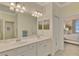 Bright bathroom featuring double sinks and an open view of the ensuite primary bedroom at 9895 Wingood Dr, Venice, FL 34292