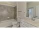 Well-lit bathroom with ceramic tile surround in shower-tub combination and white vanity with a door to the backyard at 9895 Wingood Dr, Venice, FL 34292