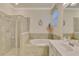 Bright primary bathroom featuring a glass enclosed shower, soaking tub and neutral tile at 9895 Wingood Dr, Venice, FL 34292