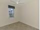 Small bedroom with a ceiling fan, tile floors, a window, and neutral colored walls at 9895 Wingood Dr, Venice, FL 34292