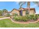 Charming single-story home with a well-manicured lawn, lush landscaping, and a paver driveway leading to the garage at 9895 Wingood Dr, Venice, FL 34292