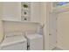 Bright laundry room with white washer and dryer, shelving, and upper cabinets at 9895 Wingood Dr, Venice, FL 34292