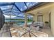A beautiful screened patio features a dining area, cozy seating around a fire pit, and a stunning lake and pool view at 9895 Wingood Dr, Venice, FL 34292