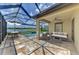 A beautiful screened patio features a dining area, cozy seating around a fire pit, and a stunning lake and pool view at 9895 Wingood Dr, Venice, FL 34292