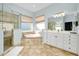 Elegant bathroom featuring a soaking tub, glass shower, and dual sink vanity at 107 Corte Del Rosa, Venice, FL 34285