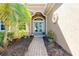 Inviting front entrance with double glass doors, a brick walkway, and lush landscaping at 107 Corte Del Rosa, Venice, FL 34285