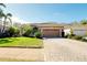 Single-story home features a tile roof, an attached garage, and lush landscaping with a brick driveway at 107 Corte Del Rosa, Venice, FL 34285