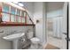 Stylish bathroom with pedestal sink, decorative mirror, and adjacent shower and toilet area at 11053 Barnsley Dr, Venice, FL 34293