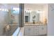 Modern bathroom with dual sinks, granite countertops, decorative mirrors and lighting fixtures, and glass shower at 19716 Fishhawk Trl, Venice, FL 34293